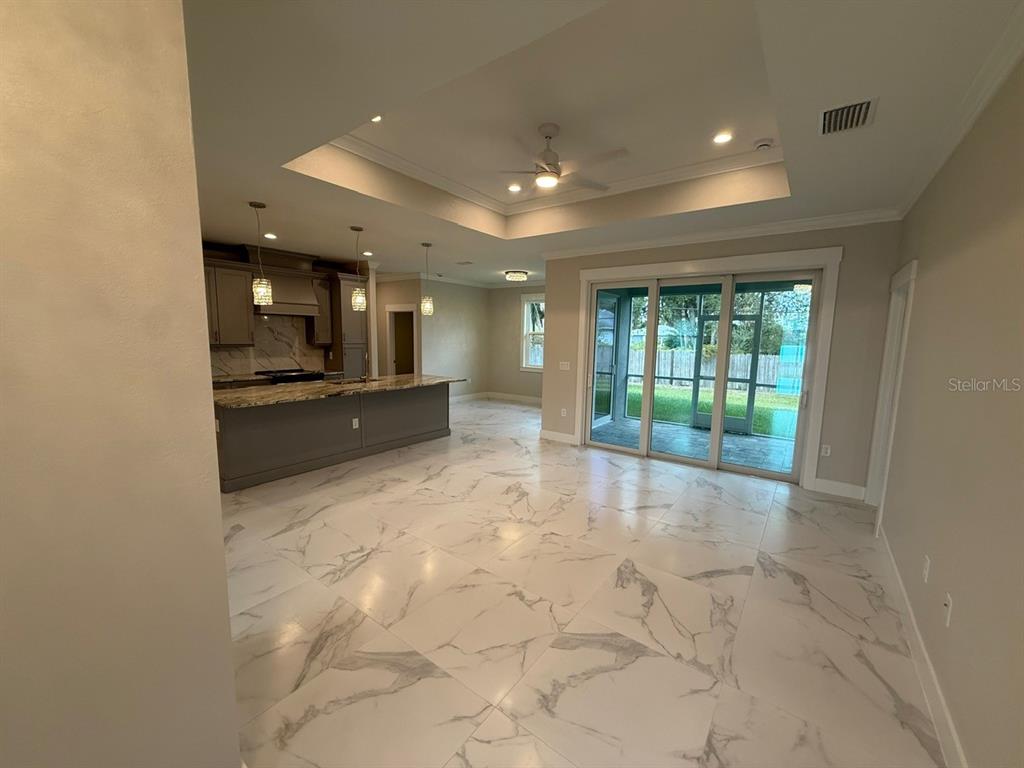 A kitchen with a large island and marble-look tile flooring opens to a covered patio — 14396 & 14422 CHAMBERLAIN BOULEVARD, PORT CHARLOTTE, FL
