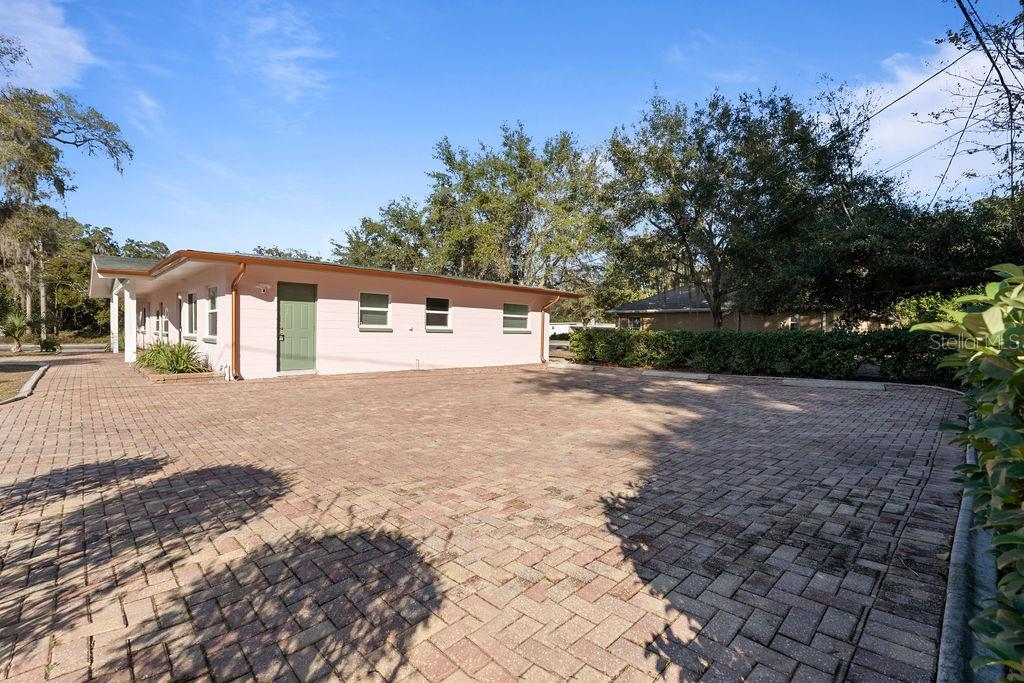 A pink, single-story building sits behind a large, paved brick driveway under a blue sky — 11987 MAPLE STREET UNIT 2, DUNNELLON, FL