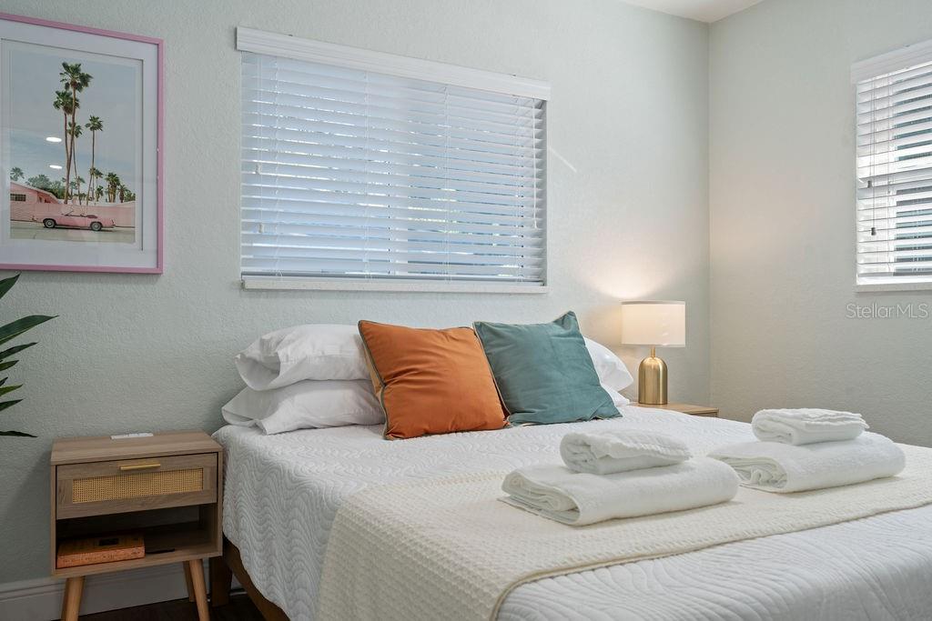 A bedroom features a bed with white bedding, two accent pillows, and a wooden nightstand — 11987 MAPLE STREET UNIT 2, DUNNELLON, FL