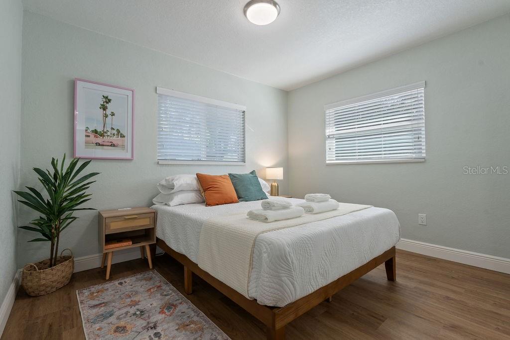 A bedroom features a bed with white bedding, two accent pillows, and light wood flooring — 11987 MAPLE STREET UNIT 2, DUNNELLON, FL