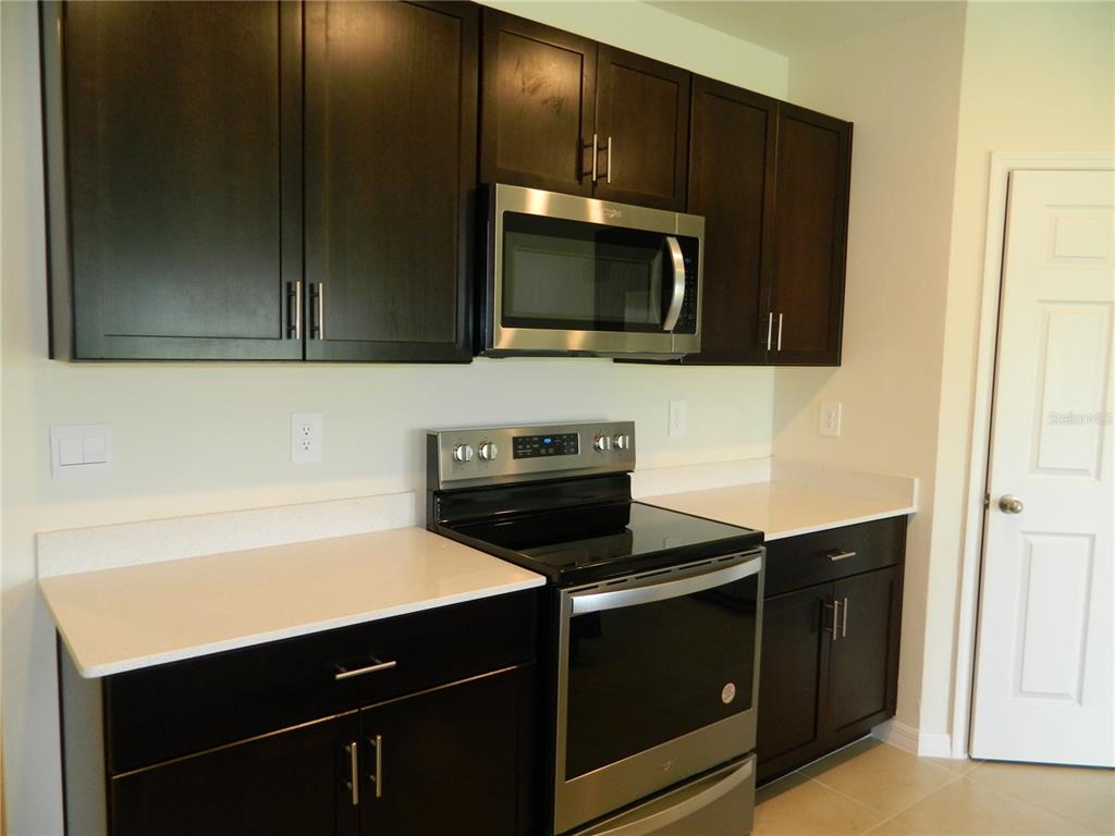 A kitchen features dark wood cabinets, stainless steel appliances, and white countertops — 25118 DOREDO DRIVE, PUNTA GORDA, FL