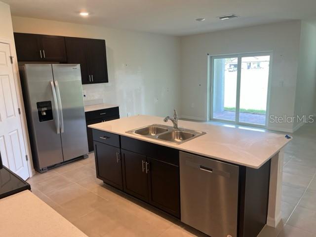 A kitchen features dark cabinets, stainless steel appliances, and a central island with a sink — 25118 DOREDO DRIVE, PUNTA GORDA, FL