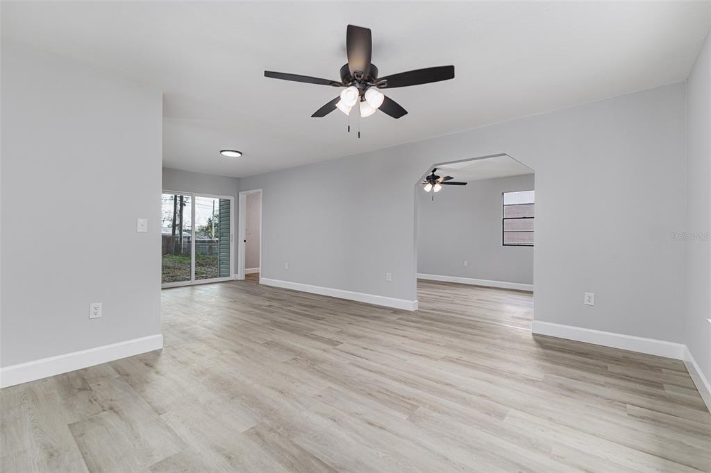 An interior view of a living room with light gray walls, wood-look flooring, and ceiling fans — 4132 CHOWEN DRIVE, LAKELAND, FL