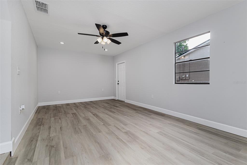 An empty room features light gray walls, wood-look flooring, a ceiling fan, and a window — 4132 CHOWEN DRIVE, LAKELAND, FL