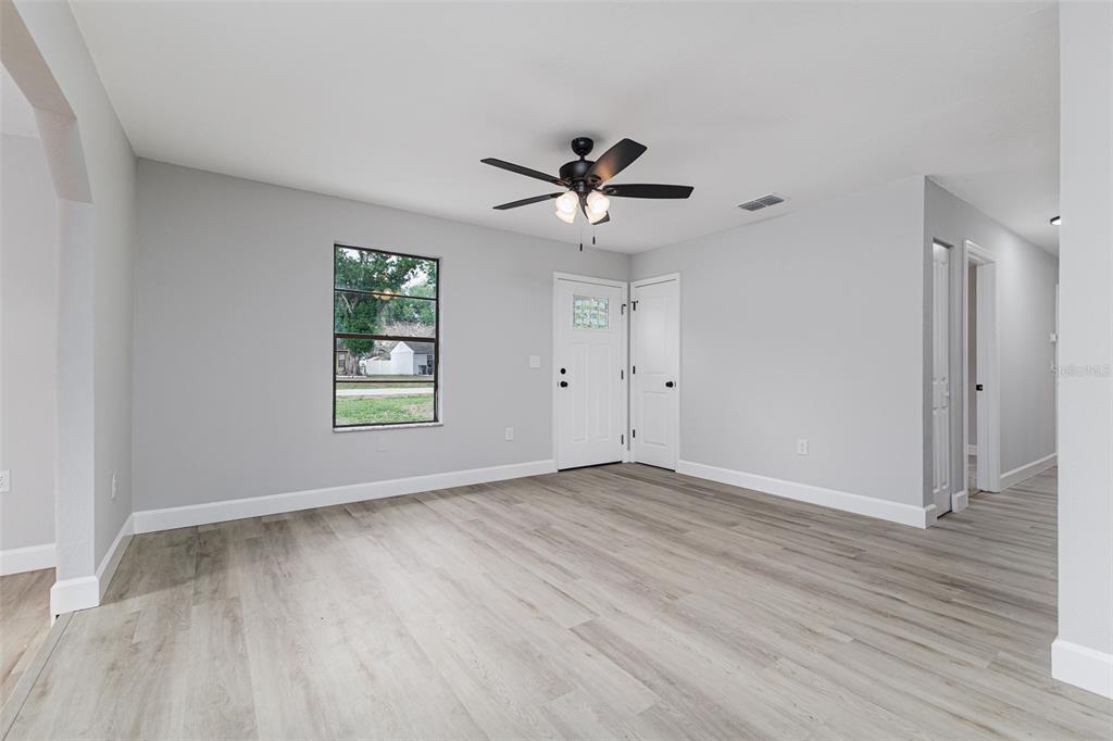 A room with light gray walls, wood-look flooring, a ceiling fan, and a front door — 4132 CHOWEN DRIVE, LAKELAND, FL
