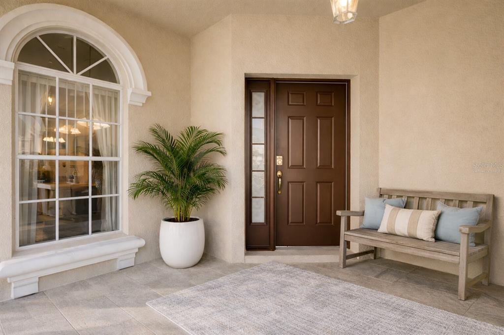 A covered entryway features a brown front door, a wooden bench, and a potted plant — 509 PINELOCH DRIVE, HAINES CITY, FL