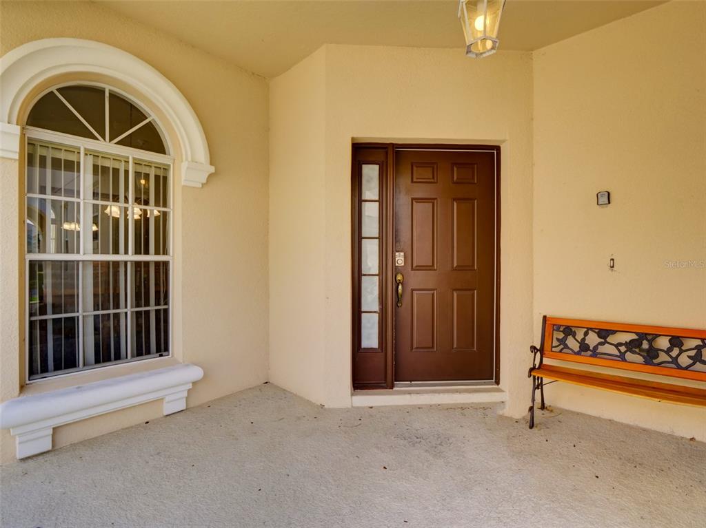 A covered front porch features a brown door, a large arched window, and a bench — 509 PINELOCH DRIVE, HAINES CITY, FL