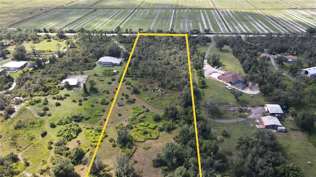 An aerial view shows a vacant, tree-covered lot outlined in yellow next to residential properties — 15650 WATER OAK COURT, PUNTA GORDA, FL