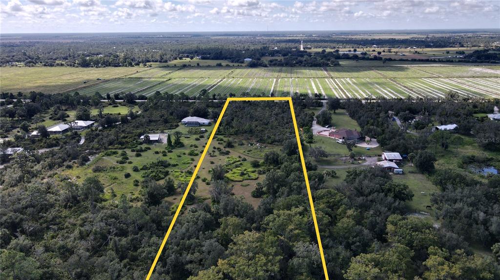 An aerial view shows a large, undeveloped rectangular lot outlined in yellow amidst rural land — 15650 WATER OAK COURT, PUNTA GORDA, FL