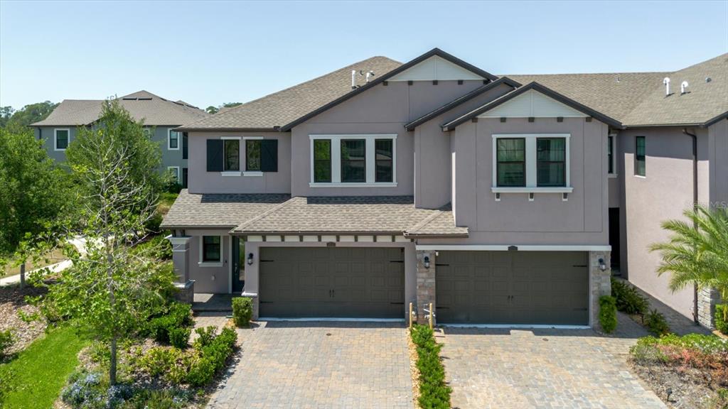 An exterior view of a two-story townhouse with two garages and a paved driveway — 4531 ALMADA LANE SE, WESLEY CHAPEL, FL