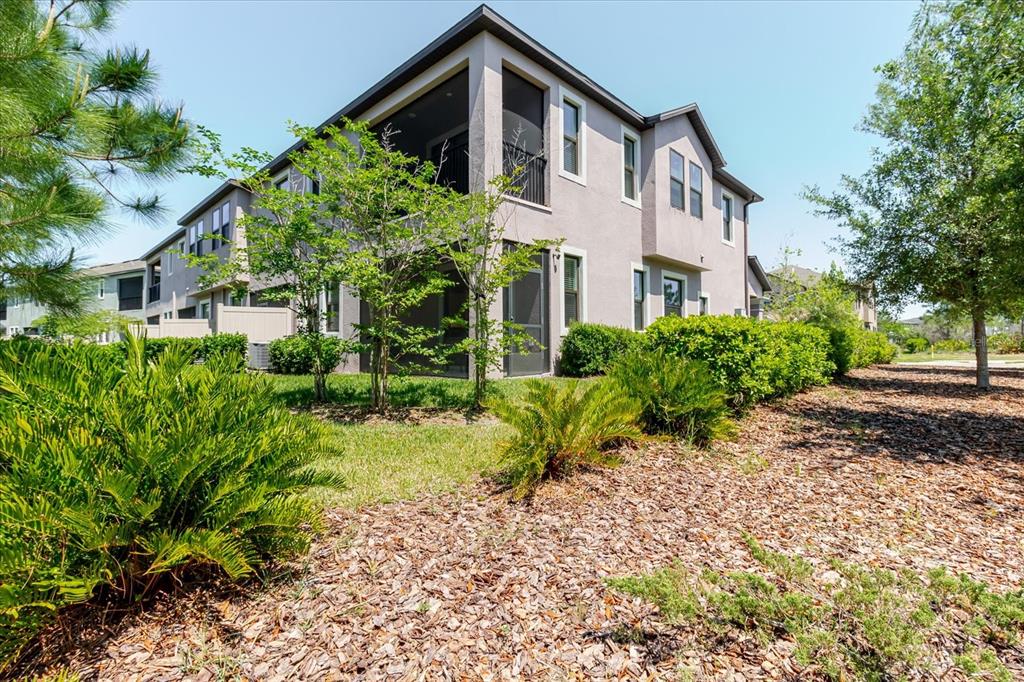 The exterior of a two-story townhouse features a screened-in porch and landscaped yard — 4531 ALMADA LANE SE, WESLEY CHAPEL, FL