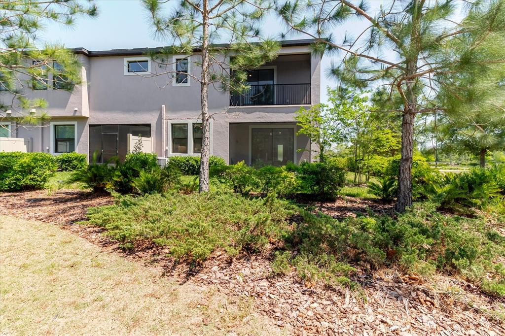 The exterior rear view of a two-story townhouse features a balcony and ground-level patio — 4531 ALMADA LANE SE, WESLEY CHAPEL, FL
