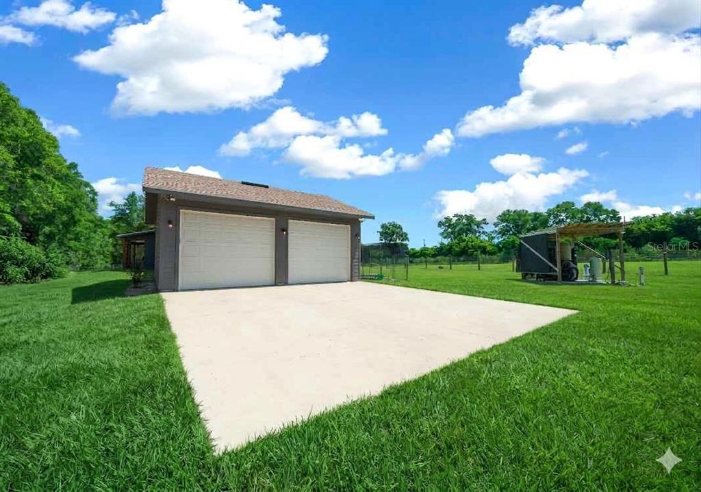 A detached two-car garage with a concrete driveway sits on a large grassy lot — 13576 NW COUNTY ROAD 235, ALACHUA, FL