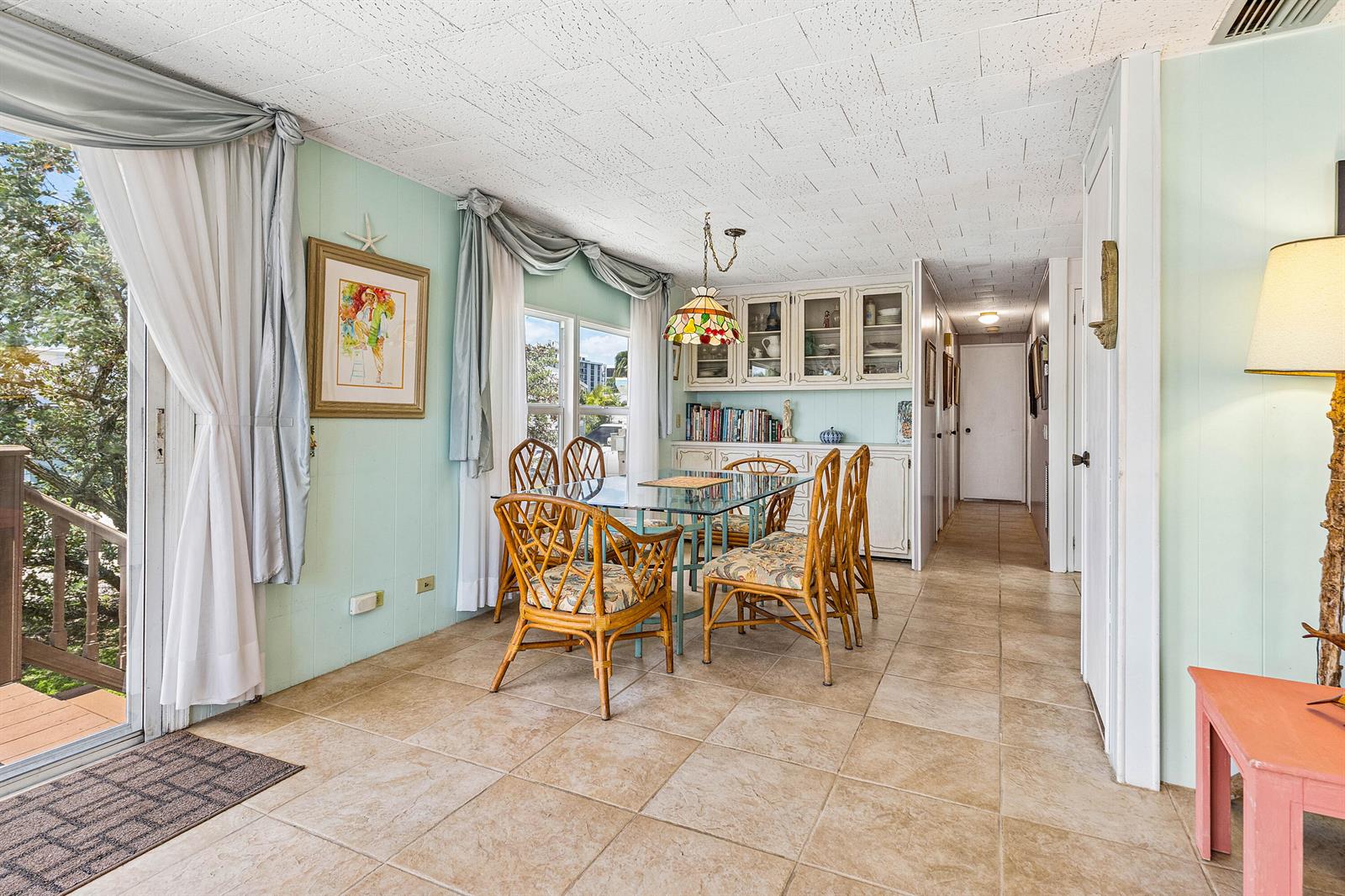 A dining room features a glass-top rattan table, tile flooring, and light green paneled walls — 205 S Ibis Drive # R, Briny Breezes FL 33435, BRINY BREEZES, FL