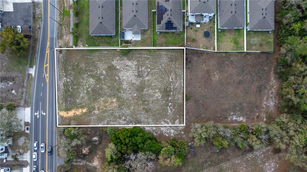 An aerial view shows a rectangular vacant lot outlined in white next to residential houses — 6211 COUNTY ROAD 547 N, DAVENPORT, FL