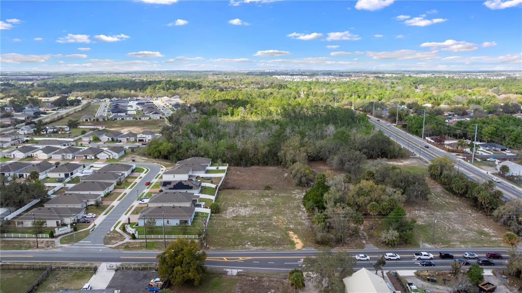 An aerial view shows a vacant rectangular lot situated between a residential neighborhood and a road — 6211 COUNTY ROAD 547 N, DAVENPORT, FL