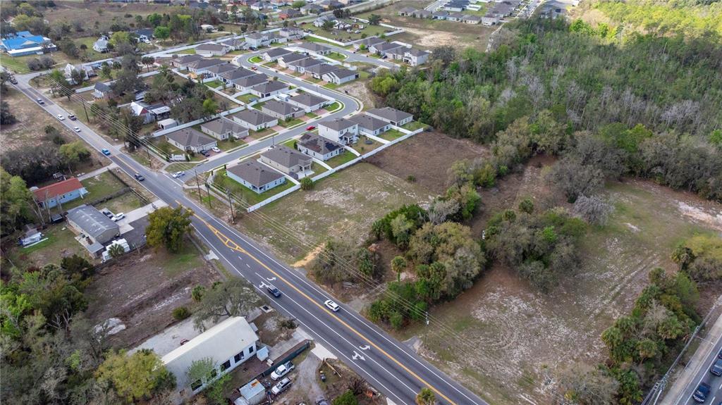 An aerial view shows a vacant lot adjacent to a residential subdivision and a road — 6211 COUNTY ROAD 547 N, DAVENPORT, FL