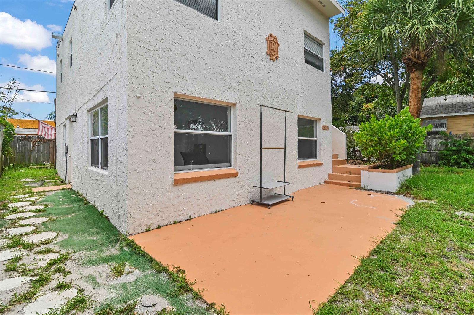 A two-story stucco building features a concrete patio, a rolling garment rack, and exterior stairs — 515 Putnam Road, West Palm Beach FL 33405, WEST PALM BEACH, FL