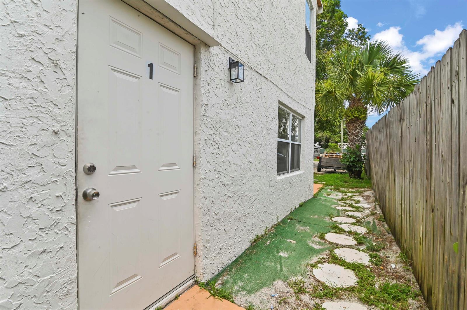 A white exterior door marked with the number one sits beside a wooden fence — 515 Putnam Road, West Palm Beach FL 33405, WEST PALM BEACH, FL