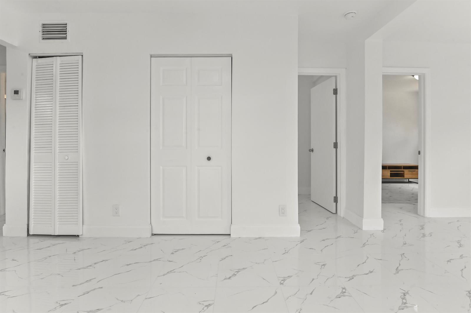 A room with white walls, white marble-patterned tile flooring, and several white interior doors — 515 Putnam Road, West Palm Beach FL 33405, WEST PALM BEACH, FL
