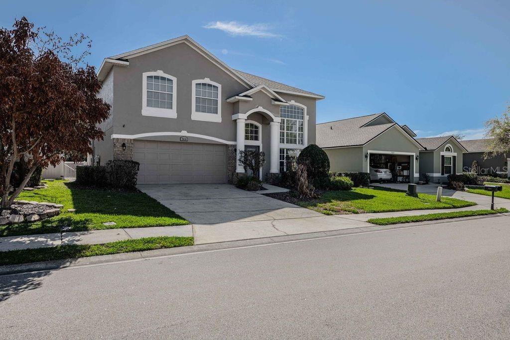 A two-story suburban house features a gray exterior, a two-car garage, and a paved driveway — 7018 CASCADES COURT, LAKELAND, FL