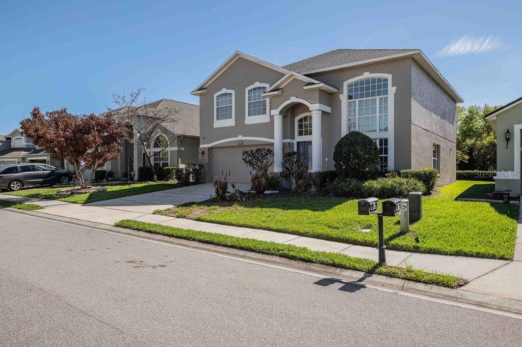 A two-story suburban house with a gray exterior, a two-car garage, and a front lawn — 7018 CASCADES COURT, LAKELAND, FL