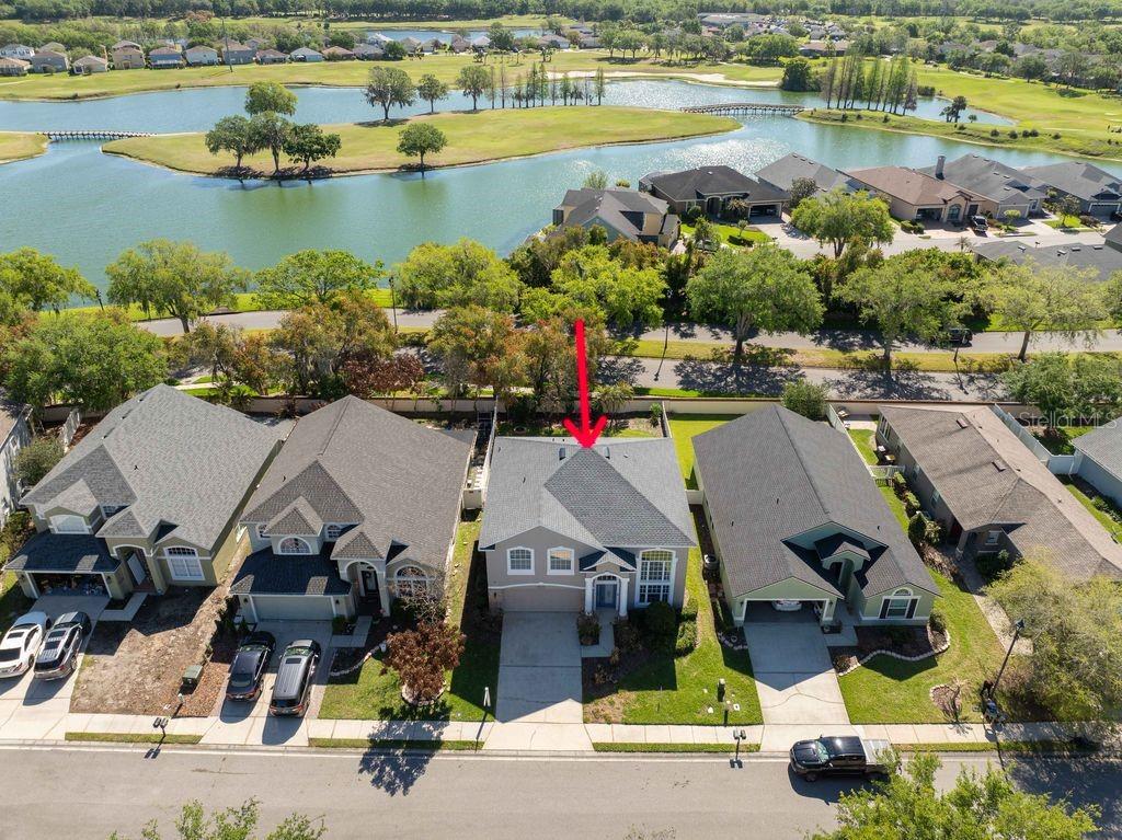 An aerial view shows a suburban house with a gray roof and a red arrow — 7018 CASCADES COURT, LAKELAND, FL