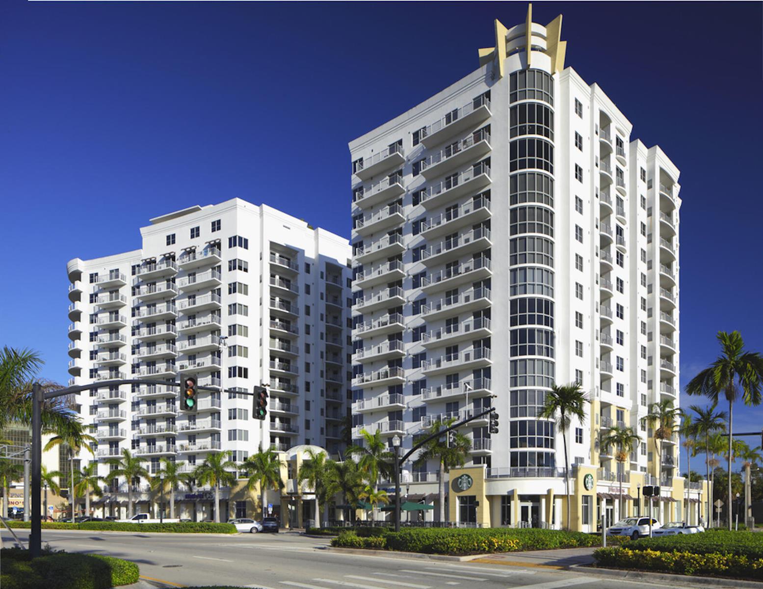 A low-angle view of two white high-rise apartment buildings with balconies and ground-floor retail — 1830 Radius Drive # 507, Hollywood FL 33020, HOLLYWOOD, FL
