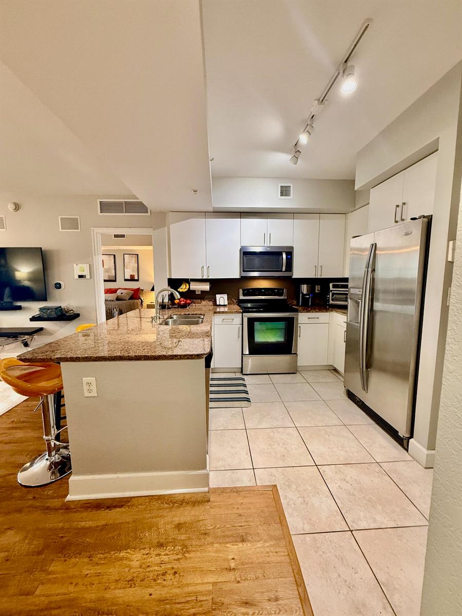 A kitchen features granite countertops, white cabinetry, stainless steel appliances, and light-colored tile flooring — 1830 Radius Drive # 507, Hollywood FL 33020, HOLLYWOOD, FL