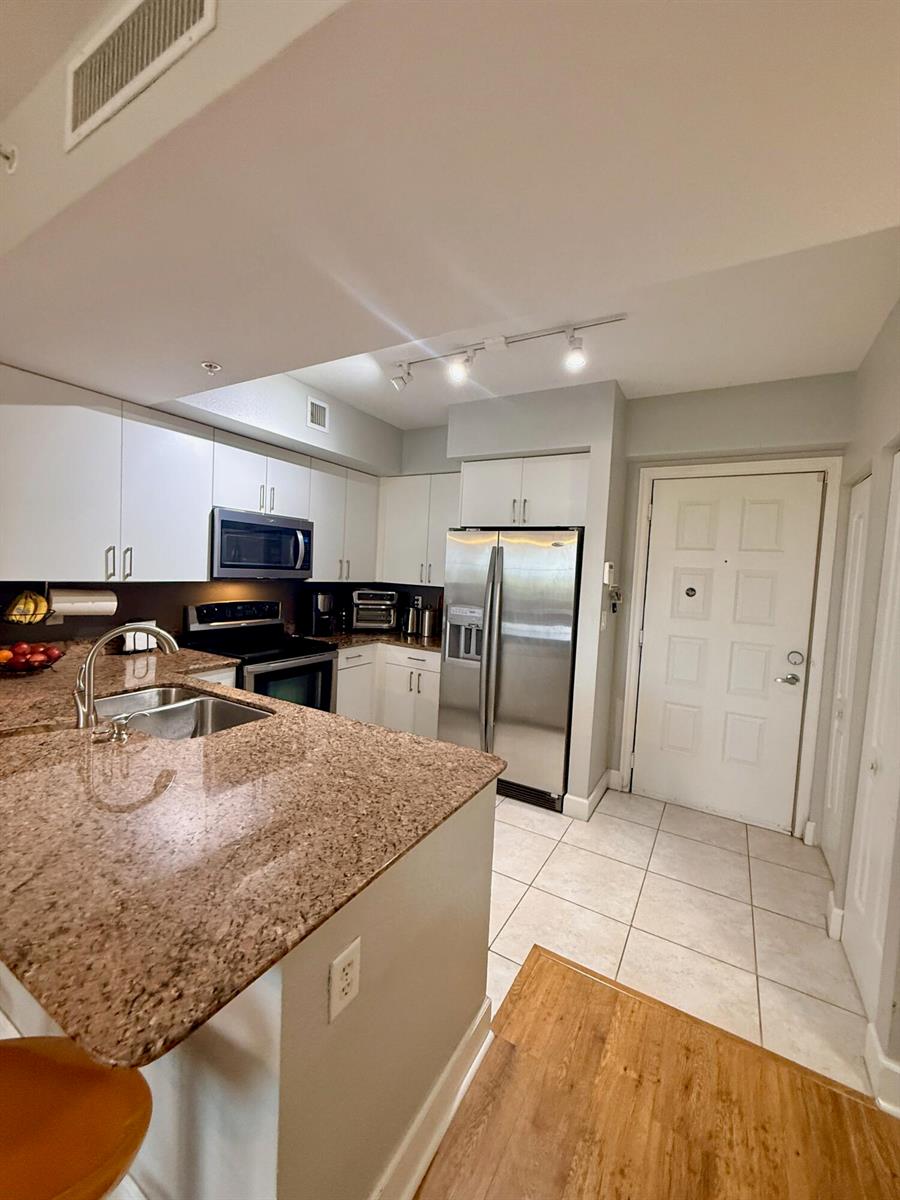 A kitchen features granite countertops, stainless steel appliances, white cabinetry, and tile flooring — 1830 Radius Drive # 507, Hollywood FL 33020, HOLLYWOOD, FL