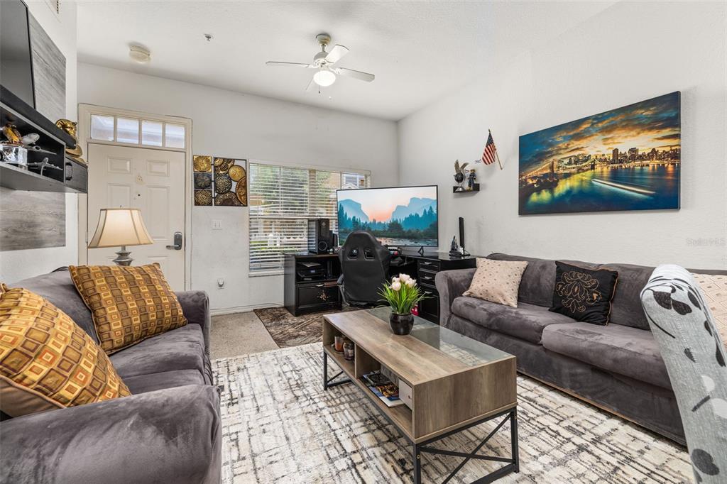 A living room features two gray sofas, a coffee table, and a computer desk area — 2620 LODI CIRCLE UNIT 103, KISSIMMEE, FL