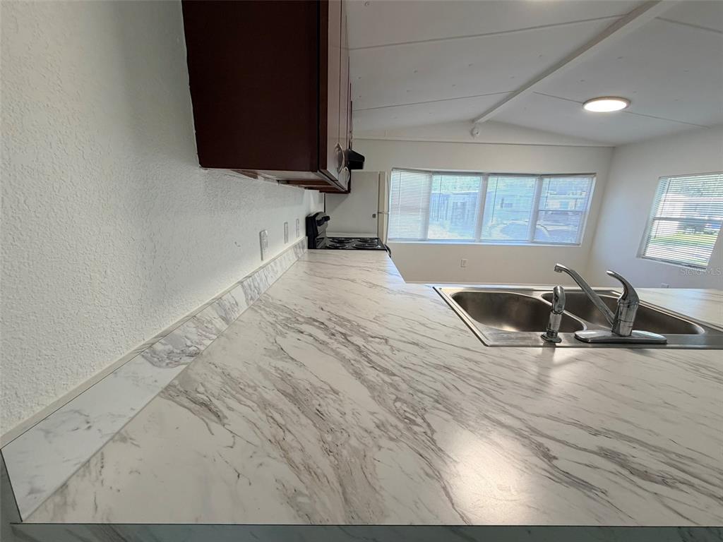 A kitchen features marble-patterned laminate countertops, a stainless steel sink, and dark wood cabinets — 6811 ROCHELLE AVENUE UNIT 6, NEW PORT RICHEY, FL