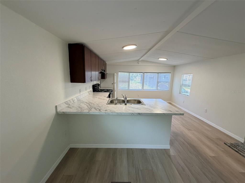 A kitchen with a marble-patterned peninsula, dark cabinets, and light wood-look flooring — 6811 ROCHELLE AVENUE UNIT 6, NEW PORT RICHEY, FL