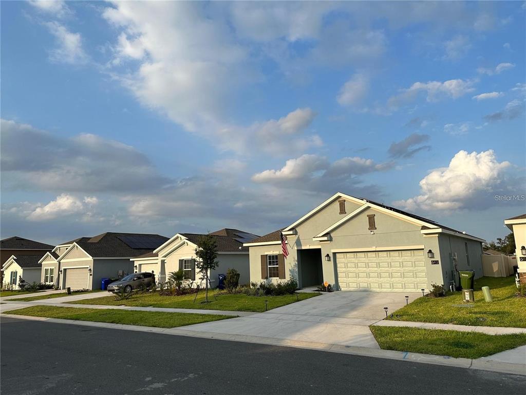 A suburban street view featuring a single-story house with a two-car garage and driveway — 643 GROVE STREET, WINTER HAVEN, FL