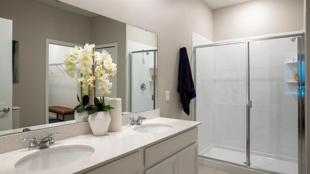 A bathroom features a double vanity with a mirror, white cabinets, and a glass-enclosed shower — 643 GROVE STREET, WINTER HAVEN, FL
