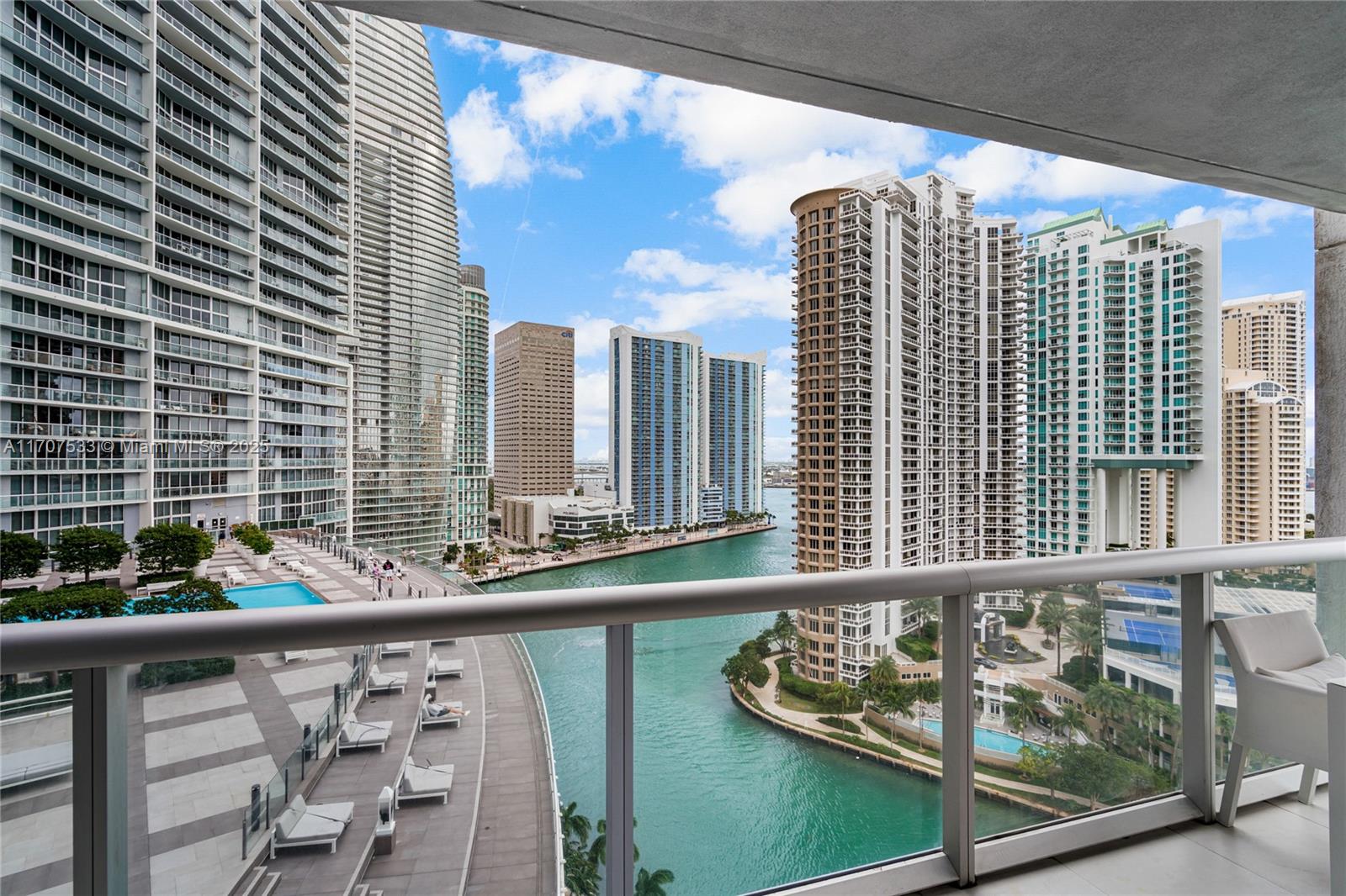A balcony view overlooks a canal, swimming pool deck, and surrounding high-rise apartment buildings — 495 Brickell Ave # 1702, Miami FL 33131, MIAMI, FL