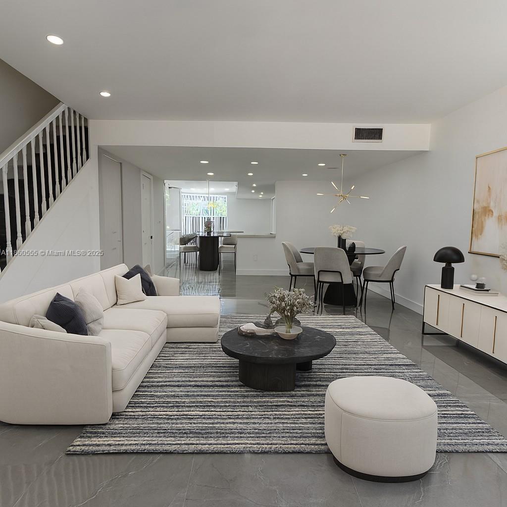 This open-concept living and dining area features a white sectional sofa, round coffee table, and tile flooring — 2318 NE 7th St # 34, Hallandale Beach FL 33009, HALLANDALE BEACH, FL
