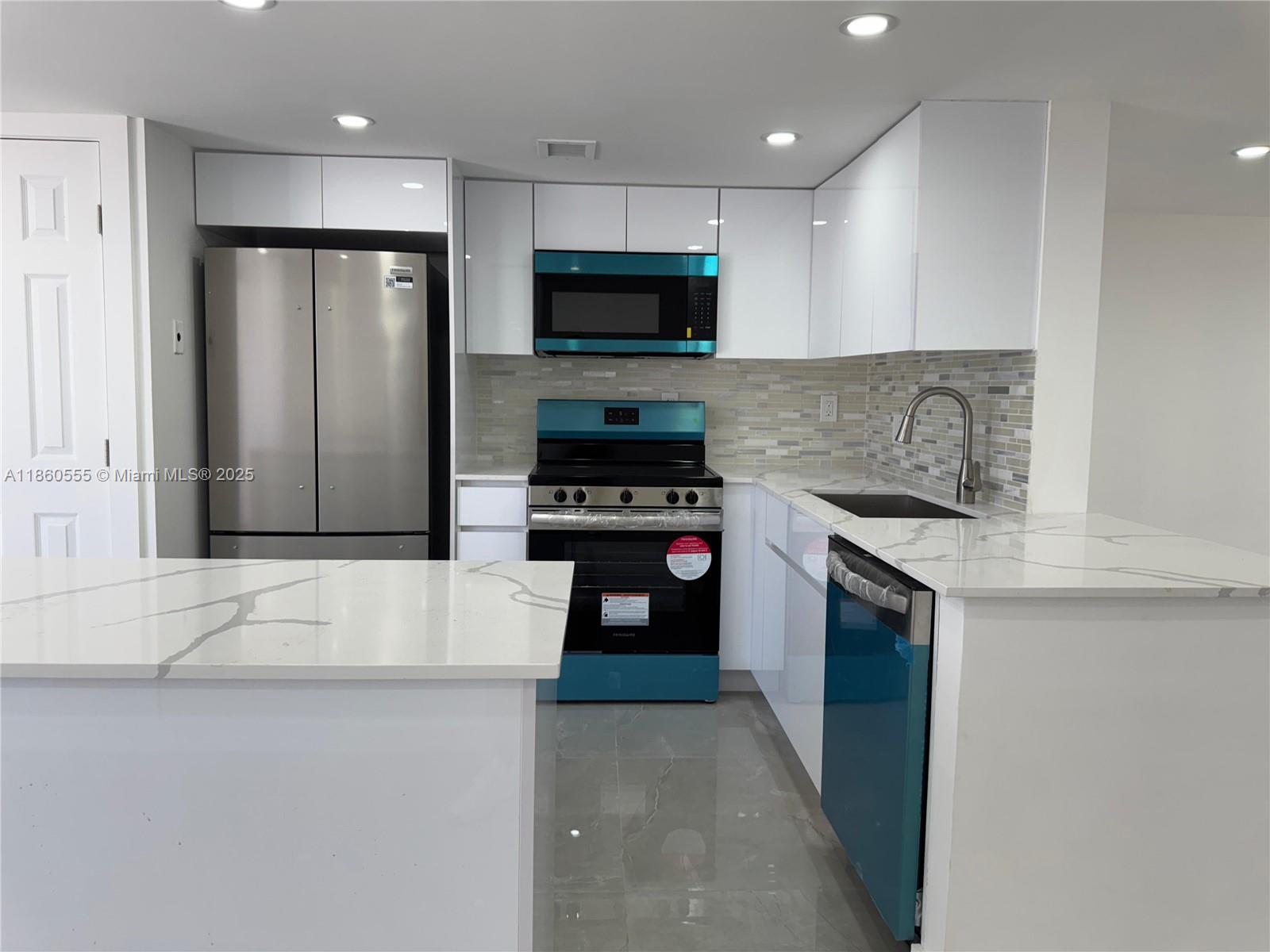 A modern kitchen features white cabinets, stainless steel appliances, and a white marble-patterned island — 2318 NE 7th St # 34, Hallandale Beach FL 33009, HALLANDALE BEACH, FL