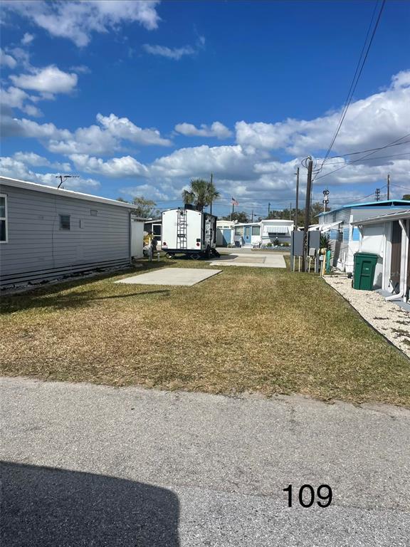 A vacant lot with a concrete pad sits between two mobile homes under a blue sky — 109 OHIO STREET, PALMETTO, FL