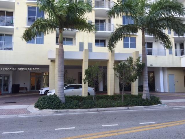 The exterior of a multi-story apartment building features palm trees and a covered entrance area — HOLLYWOOD, FL