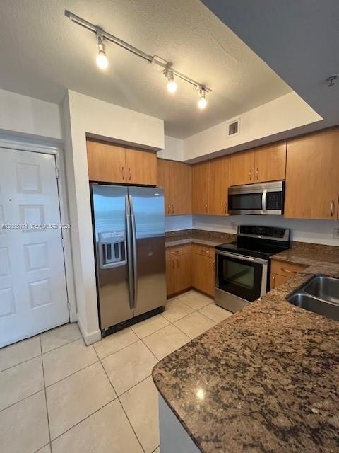 A kitchen features light wood cabinets, stainless steel appliances, and granite countertops with tile flooring — HOLLYWOOD, FL