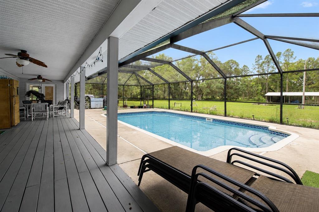 A screened-in pool area features a covered wooden deck and a rectangular swimming pool — 128 NE 326TH AVENUE, CROSS CITY, FL