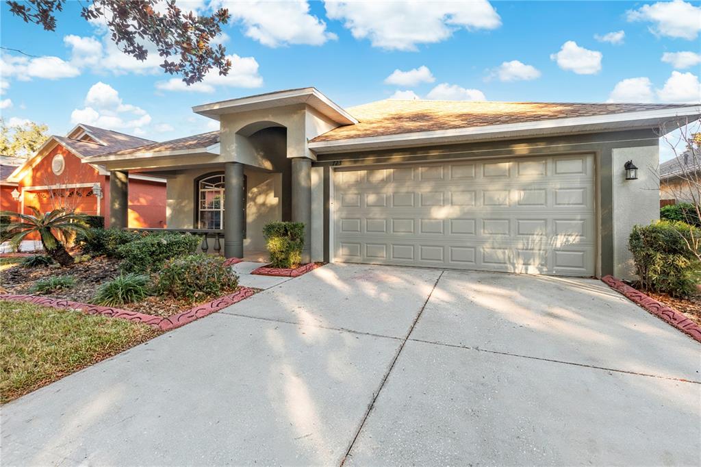 A single-story house with a beige stucco exterior, a two-car garage, and a covered porch — 723 ERIK LAKE ROAD, BRANDON, FL