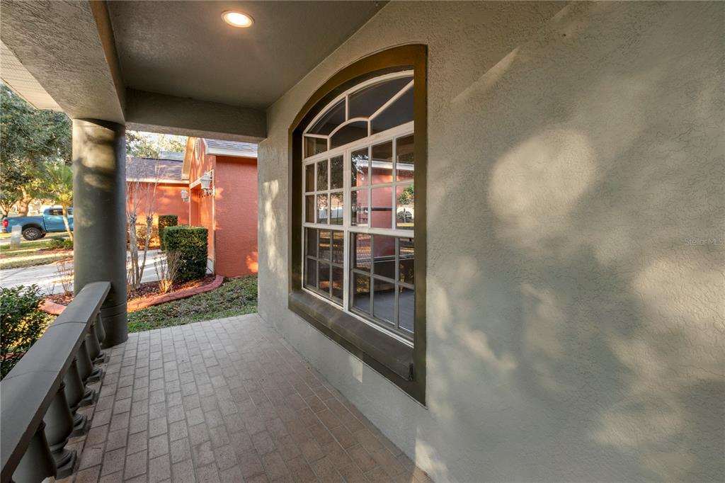 A covered front porch features a brick floor, a large arched window, and a column — 723 ERIK LAKE ROAD, BRANDON, FL