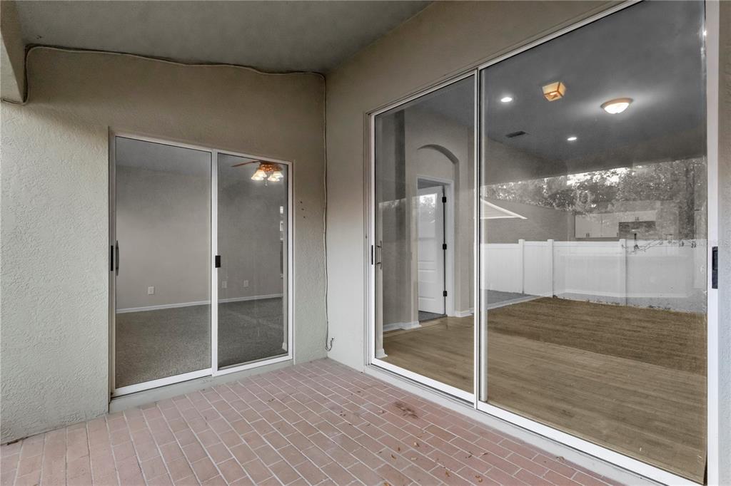 A covered patio with brick flooring features two sets of sliding glass doors — 723 ERIK LAKE ROAD, BRANDON, FL