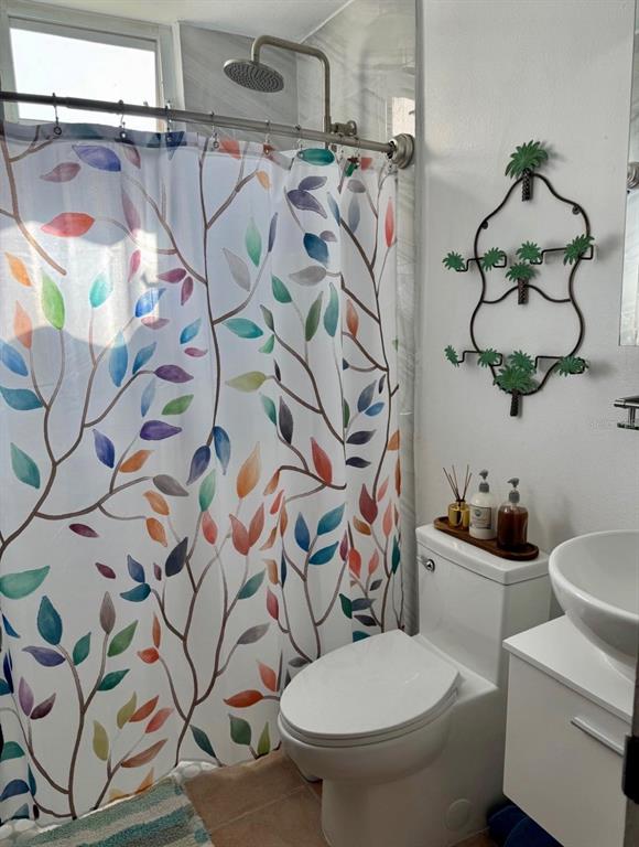 A bathroom features a colorful leaf-patterned shower curtain, a white toilet, and a wall-mounted rack — 5015 PUNTA TUNA UNIT 309, MAUNABO, PR