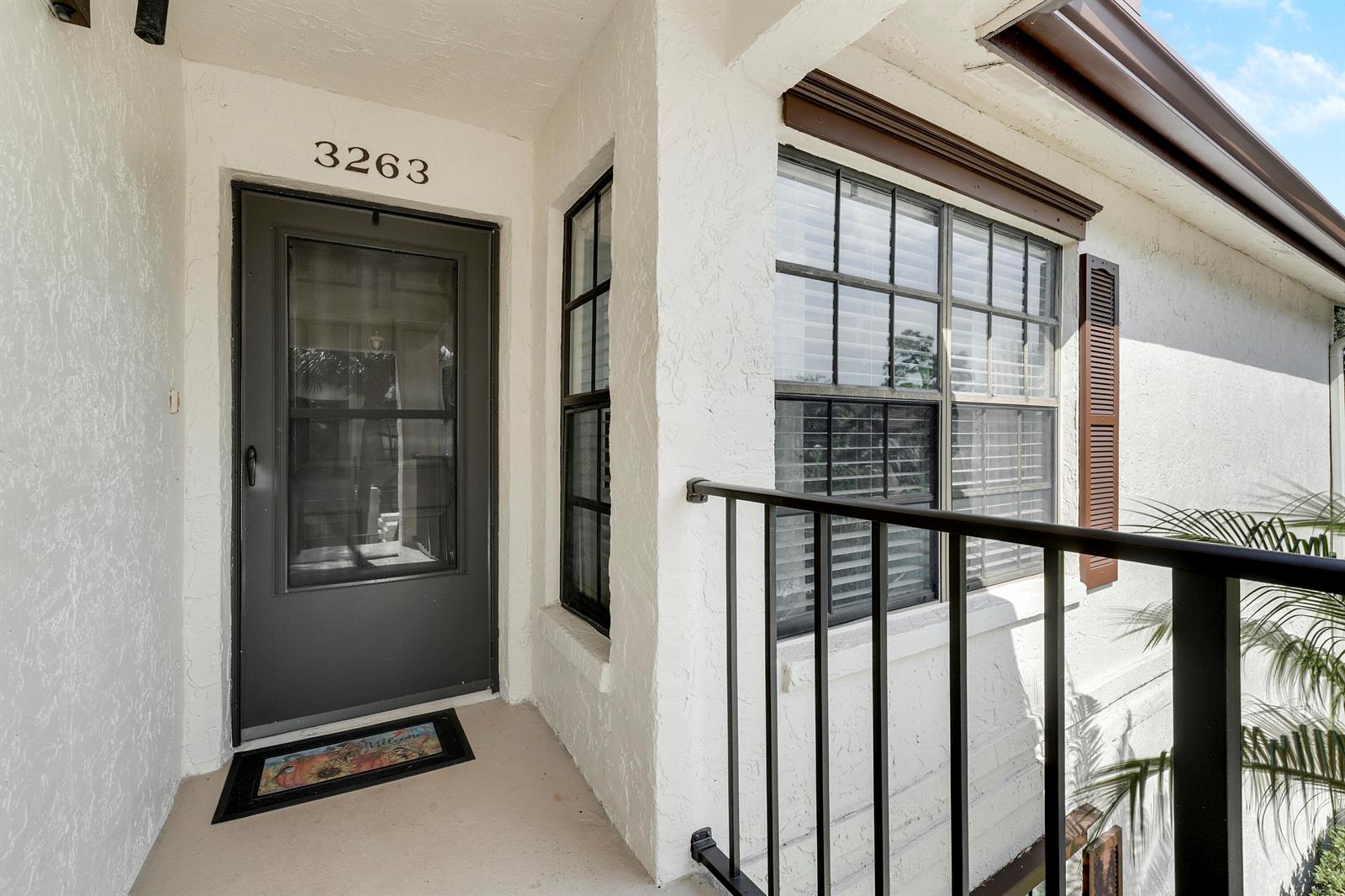 An exterior view of a residential entryway featuring a dark door, window, and metal railing — 3263 Perimeter Drive, FL 33467, FL