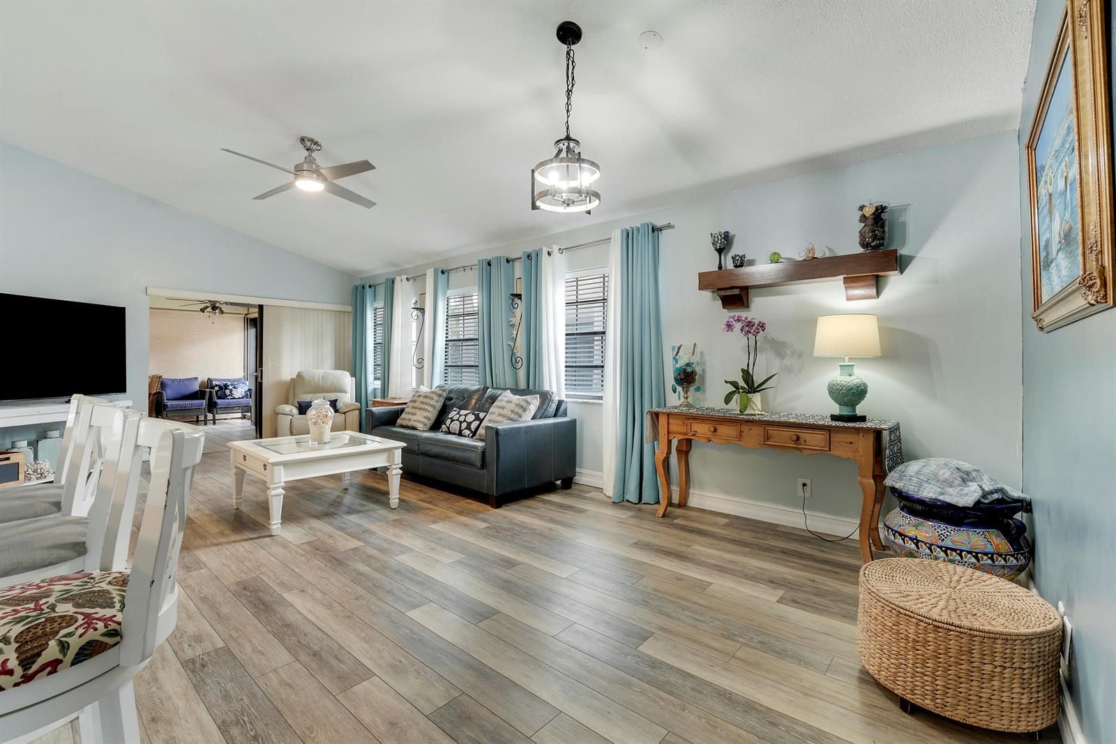 A living room with light blue walls, wood-look flooring, a dark sofa, and a console table — 3263 Perimeter Drive, FL 33467, FL