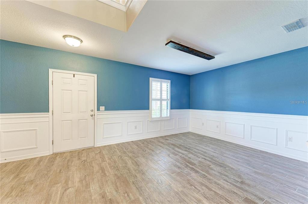 An empty room features blue walls, white wainscoting, wood-look tile flooring, and a ceiling light — 2084 LA PALMA AVENUE, PORT CHARLOTTE, FL