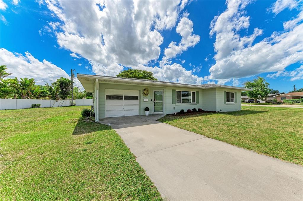 A light green single-story house with a white garage door and a concrete driveway — 2811 33RD AVENUE W, BRADENTON, FL